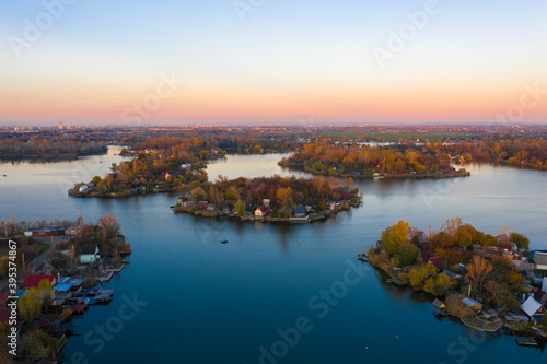 Szigetszentmiklós, Hungary - Aerial drone view of a tiny fishing island on Lake Kavicsos (Kavicsos to) near Budapest. The island is full with fishing huts, piers and cabins. Warm autumn colors.