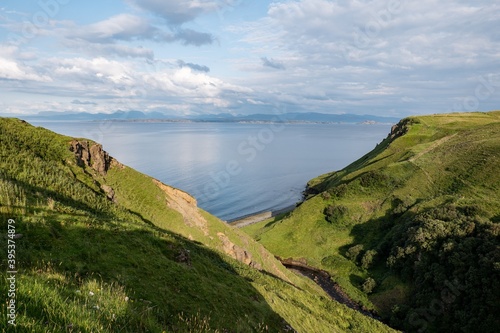 Green Scottish landscape with hills and deep gorge near Staffin at Isle of Skye with pastures during sunset