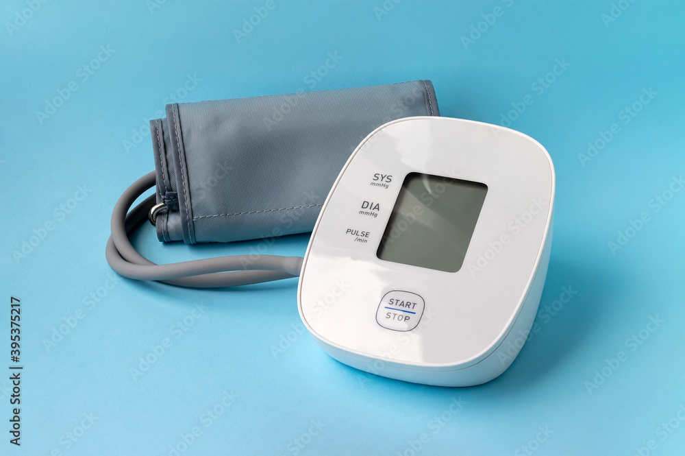 Automatic blood pressure monitor on blue background. Medical electronic tonometer Automatic blood pressure monitor on blue background. Medical electronic tonometer