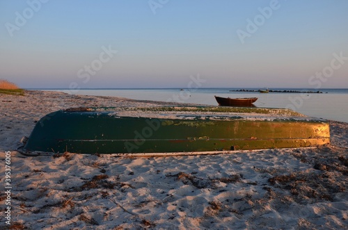 Before sunset on a beach on island Ruegen in Germany, Mecklenburg West Pomerania, two fishing boats in the Baltic sea, one upturned in the sand