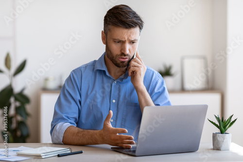 Male Entrepreneur Having Problems With Computer At Work, Talking With Customer Support