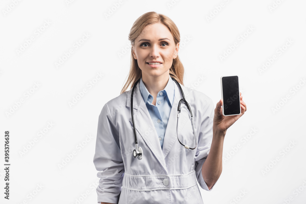 nurse in white coat smiling while holding smartphone with blank screen isolated on white nurse in white coat smiling while holding smartphone with blank screen isolated on white