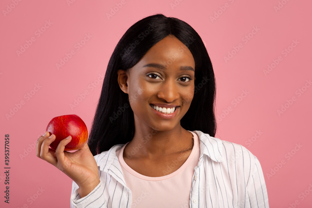 Portrait of happy black woman with tasty red apple on pink studio background, panorama Portrait of happy black woman with tasty red apple on pink studio background, panorama
