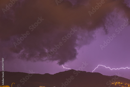 Strong thunder-storm above night mountains and city. Large Bright Lightning Close up. Mediterranian winter night thunderstorm. Alanya, Turkey.