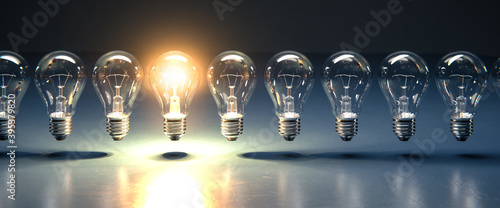 A row of lightbulbs with one brigthly lit - concept for having an idea, innovation, standing out. Web banner size