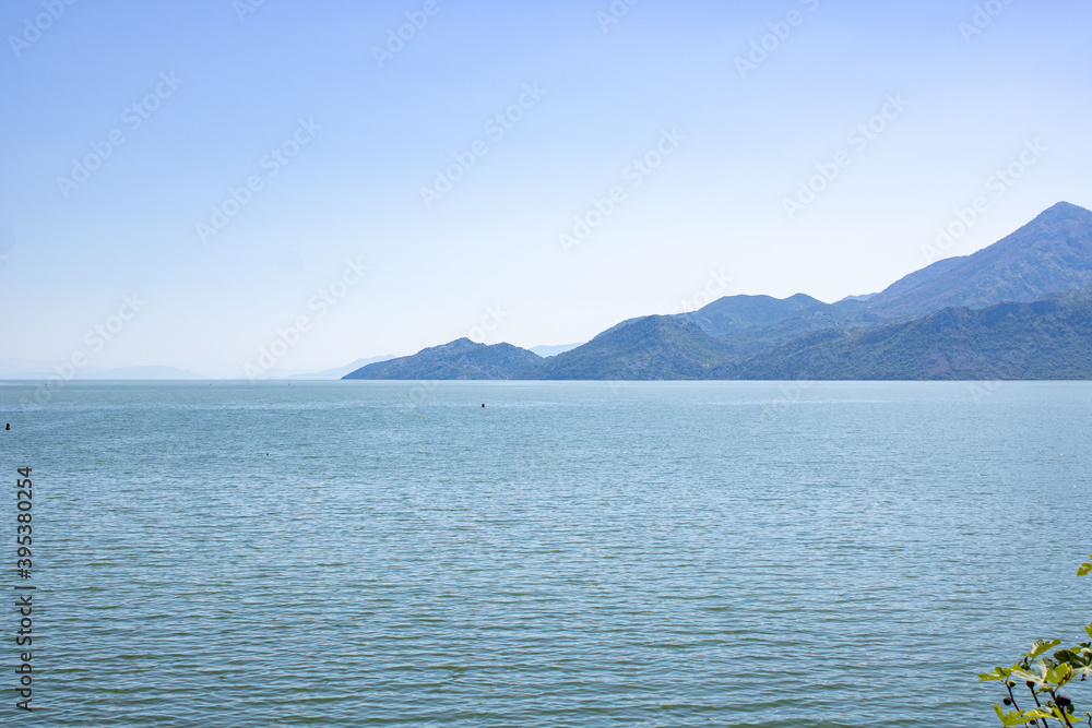 A beautiful view of the Skadar (Skoderskoe) lake among the mountains. Mountain landscape in the haze. Montenegro.