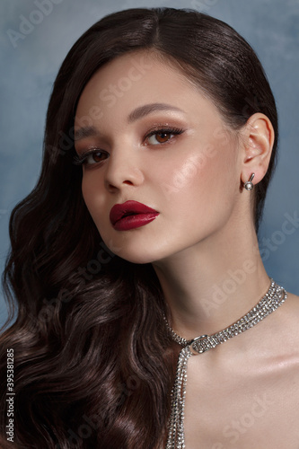 Vintage portrait of a beautiful brunette girl with bright evening makeup on a gray background.