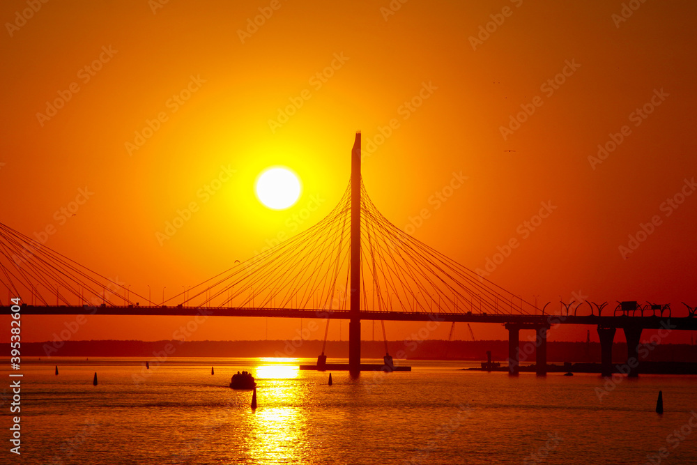 sunset over the cable-stayed bridge reflecting in the river water