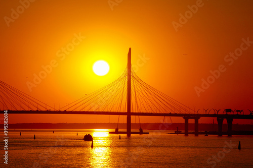 sunset over the cable-stayed bridge reflecting in the river water © Sergey