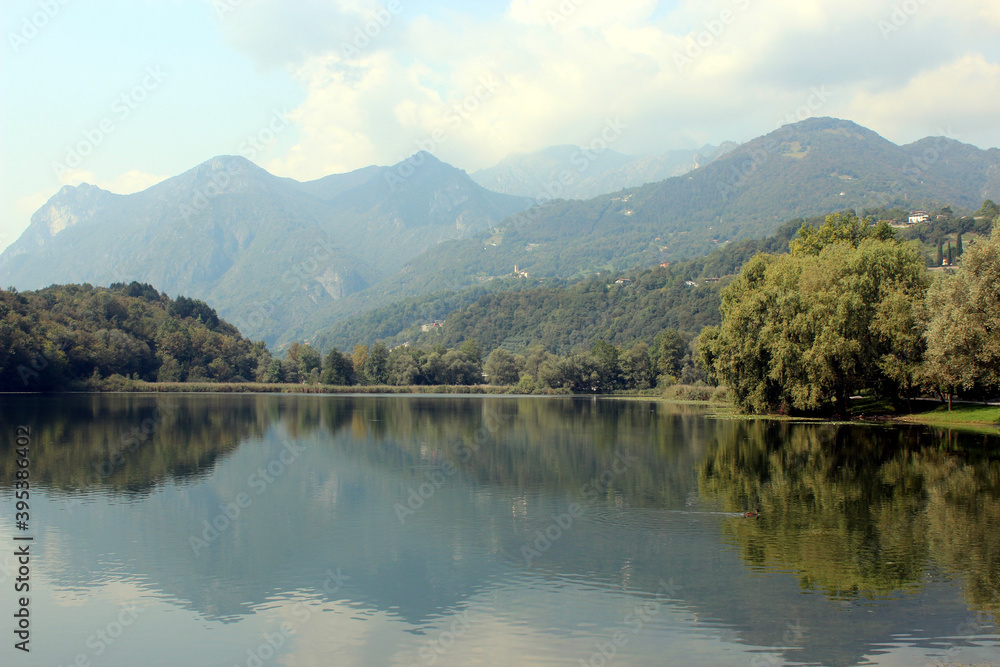 Beautiful panoramic view over a small Italian lake with the Alps in the distance. Photo was taken on a sunny day in summer.