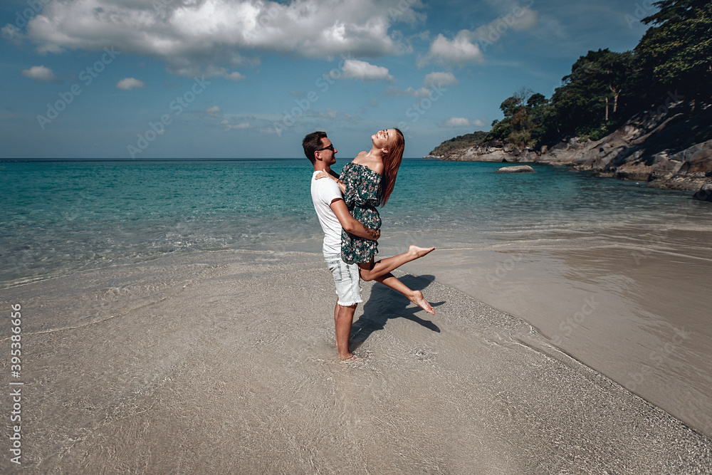 Caucasian man carrying his red haired girlfriend enjoying a late afternoon together at the beach. Phuket. Thailand. Caucasian man carrying his red haired girlfriend enjoying a late afternoon together at the beach. Phuket. Thailand.