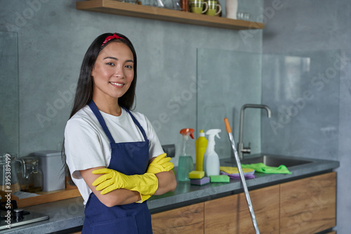 For a cleaner place. Portrait of pretty young woman cleaning lady wearing protective gloves, smiling at camera, ready for cleaning the house