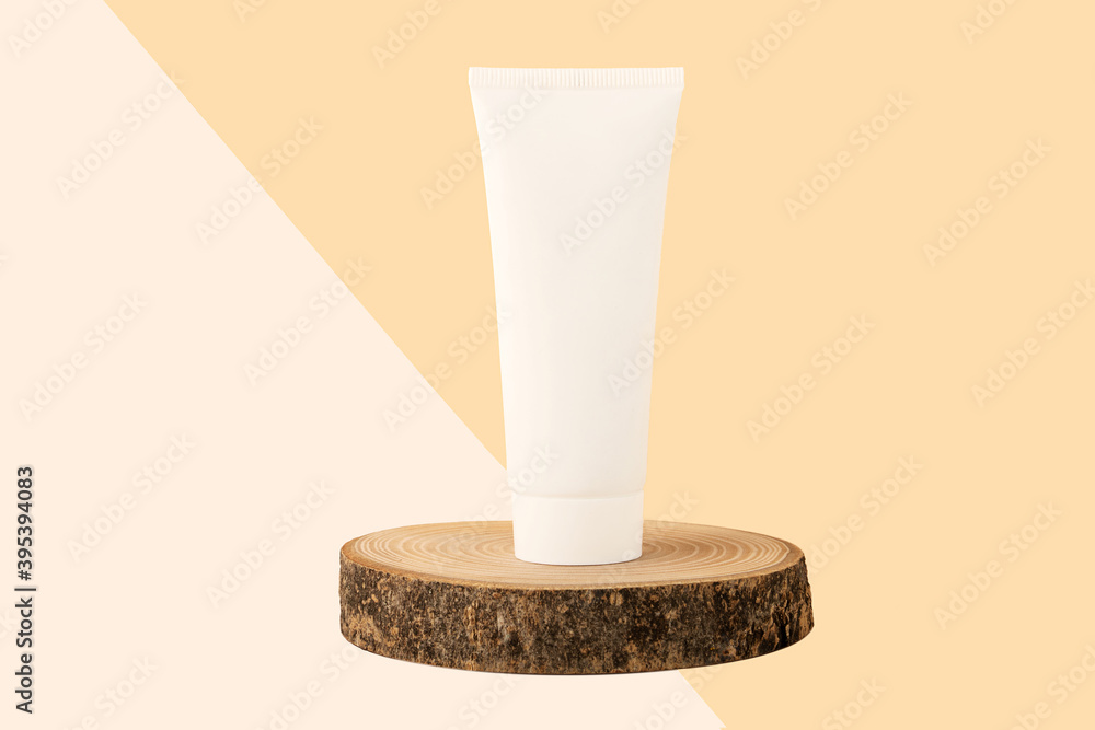 Blank cosmetics tube stand on the top of wood cut.Beautiful pastel beige isometric background.Organic copcept. Blank cosmetics tube stand on the top of wood cut.Beautiful pastel beige isometric background.Organic copcept.