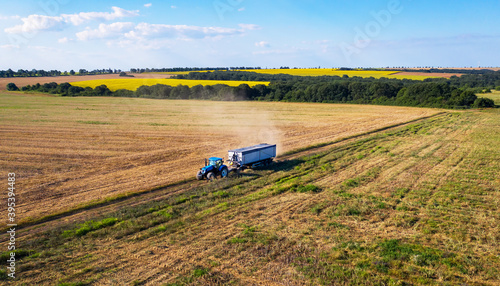 Tractor pulling trailer in sunny rural field.