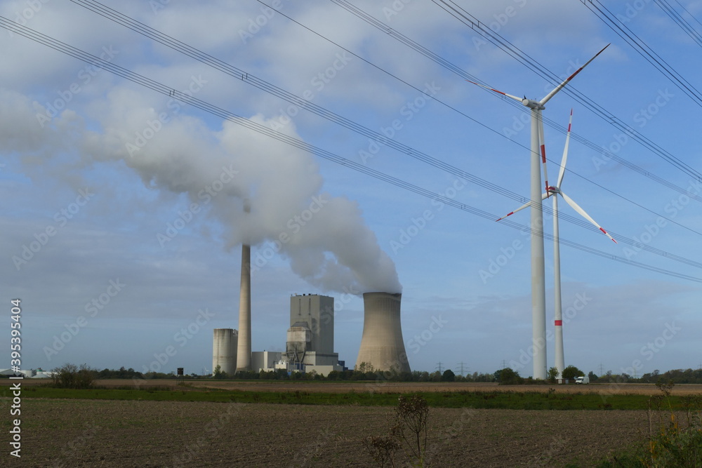 Coal-fired power plant next to wind turbines under high-voltage lines, old technology next to renewable energy near the village Peine Mehrum, Lower Saxony, Germany.