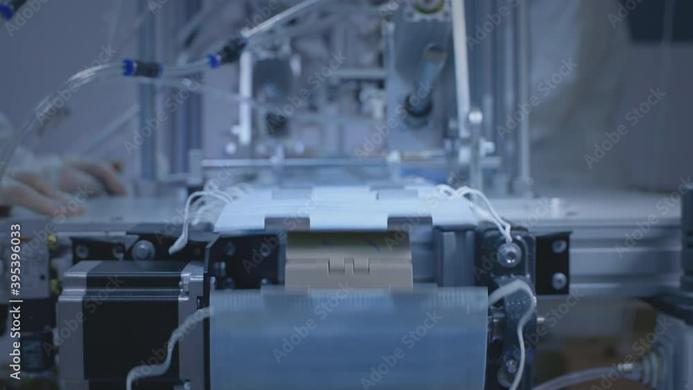 Production of medical protective face masks for air filtration. Coronavirus protection machine, covid-19. Masks move on a conveyor, production line. Industry during a pandemic or quarantine. Production of medical protective face masks for air filtration. Coronavirus protection machine, covid-19. Masks move on a conveyor, production line. Industry during a pandemic or quarantine.