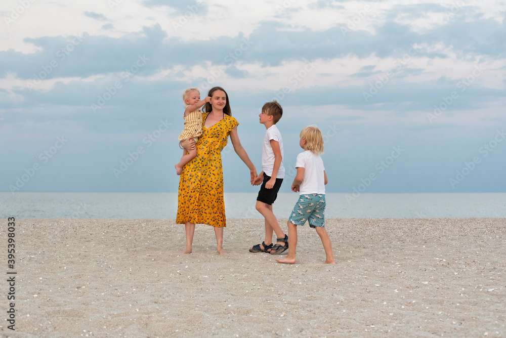 Happy family on beach. Family lifestyle. Mom and three children having fun on the sea