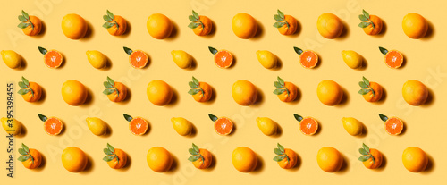 Citrus fruits pattern: lemons, mandarine, tangerine and oranges on yellow background. Hard light.