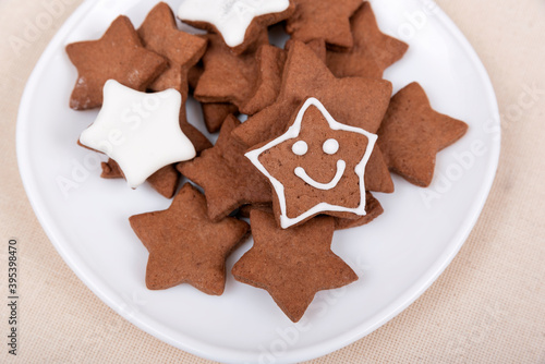 Tasty glazed painted cookies stars with smile on white plate. Gingerbread cookie