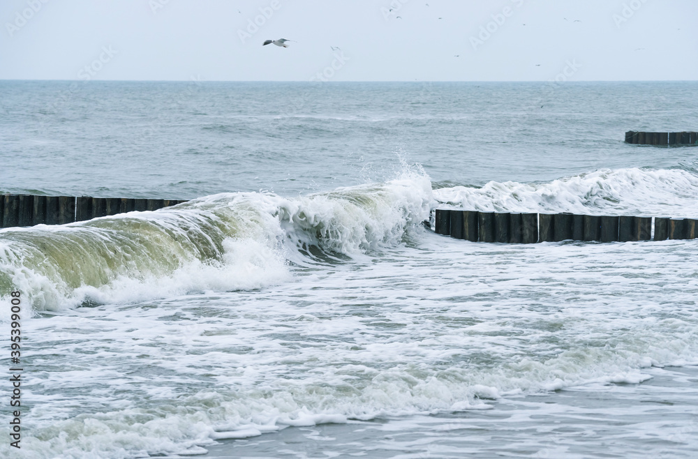 The wooden breakwater cuts the wave.