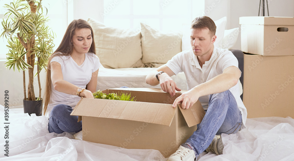 Portrait of happy couple looking at laptop computer together sitting in new house, surrounded with boxes Portrait of happy couple looking at laptop computer together sitting in new house, surrounded with boxes