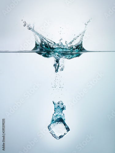 Ice cube splashing into clear water surface view