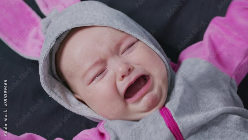 A Baby Lies on the Bed and Cries. Child is Upset and Crying. A Baby Lies on the Bed and Cries. Child is Upset and Crying.