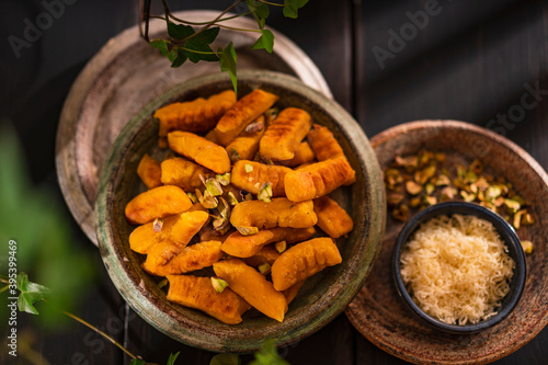 Gnocchi with a pumpkin and cheese. Autumn meal. Top view table scene on a brown rustic wooden background with copy space. Fried vegetable nyokki. Vegan, healthy food.