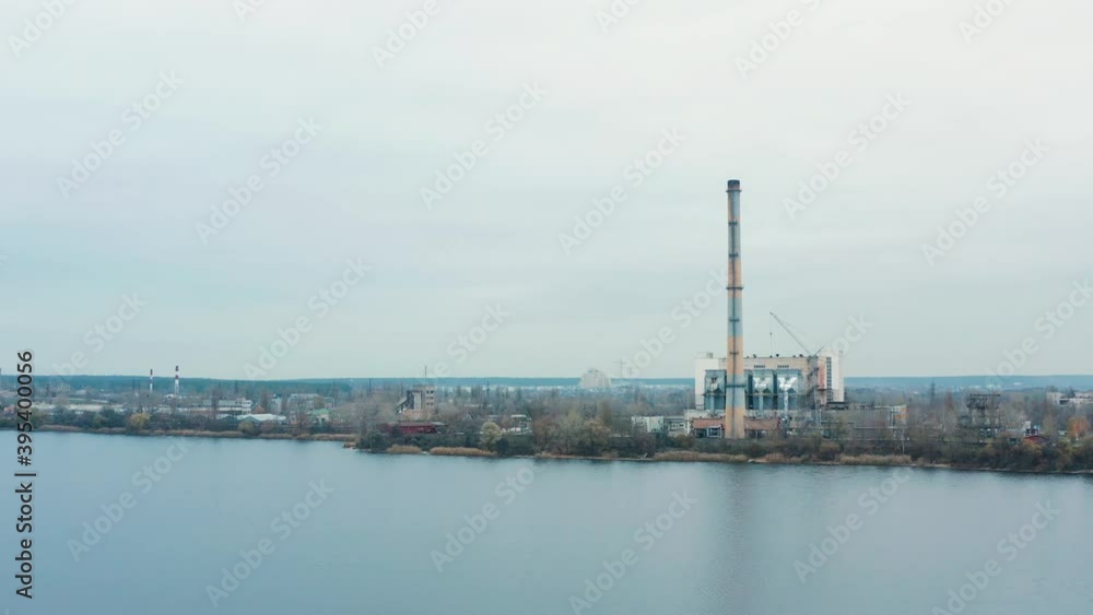 Aerial view of the Industrial Plant with Smoking Pipes near the City. Industrial zone. View from the drone to the Metallurgical factory near the river. Poor environmental conditions of the environment Aerial view of the Industrial Plant with Smoking Pipes near the City. Industrial zone. View from the drone to the Metallurgical factory near the river. Poor environmental conditions of the environment