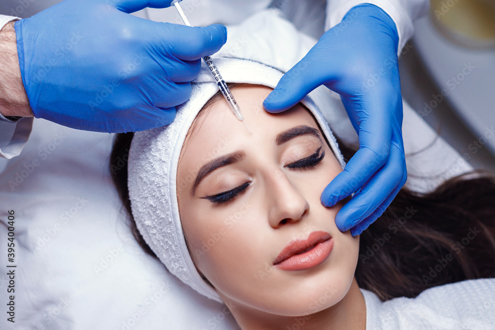 Beautiful woman getting lifting injection in forehead. Close-up woman hyaluronic acid injection. Botox Injections of skin rejuvenation. Cosmetic procedures, botox injections, hyaluronic acid. Beautiful woman getting lifting injection in forehead. Close-up woman hyaluronic acid injection. Botox Injections of skin rejuvenation. Cosmetic procedures, botox injections, hyaluronic acid.