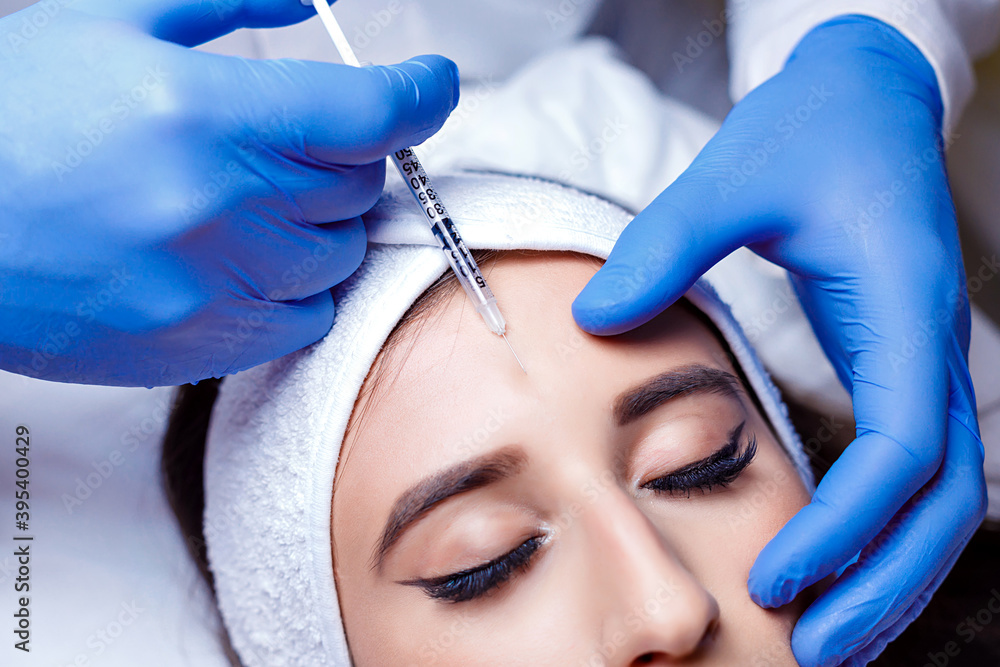 Beautiful woman getting lifting injection in forehead. Close-up woman hyaluronic acid injection. Botox Injections of skin rejuvenation. Cosmetic procedures, botox injections, hyaluronic acid. Beautiful woman getting lifting injection in forehead. Close-up woman hyaluronic acid injection. Botox Injections of skin rejuvenation. Cosmetic procedures, botox injections, hyaluronic acid.