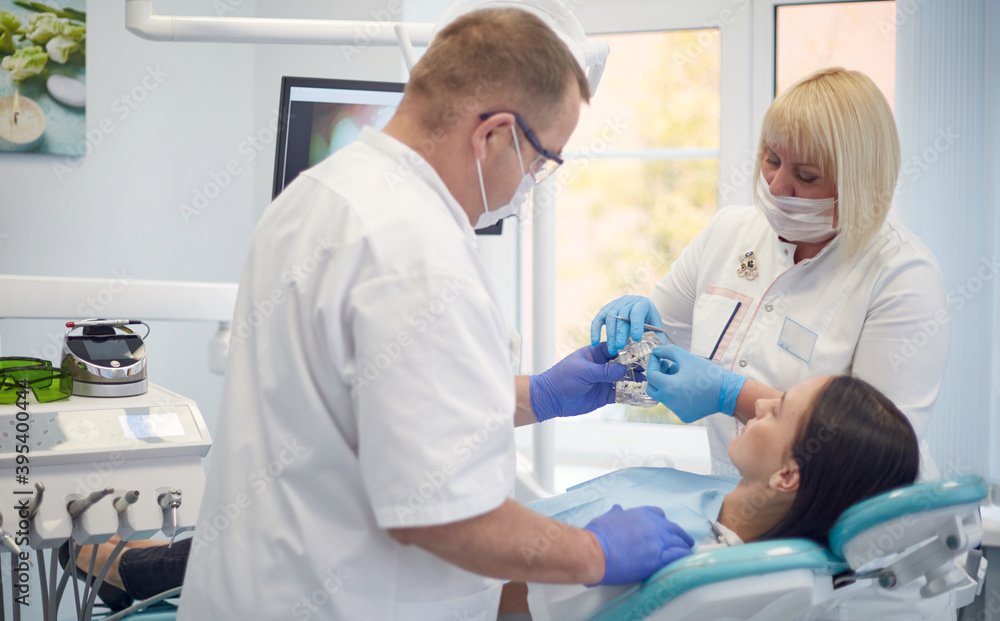 Fototapeta premium Doctor dentist treats teeth of a beautiful young girl patient. The girl on reception at the dentist. Doctor dentist treats tooth
