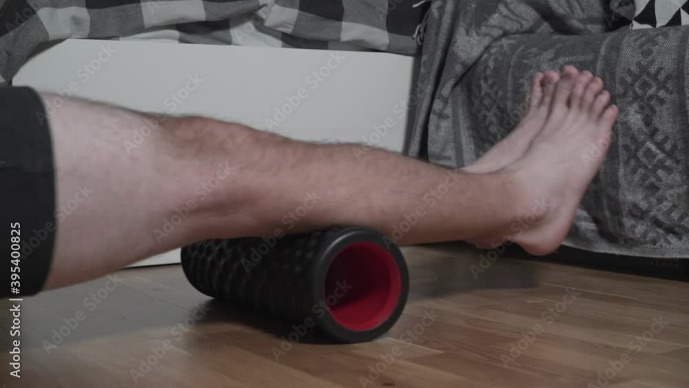 Exercise on foam roller to massage tired, over-tense muscles after training. Fit young man massaging muscles with foam roller after practice at home. Sport, fitness and healthy lifestyle in apartment Exercise on foam roller to massage tired, over-tense muscles after training. Fit young man massaging muscles with foam roller after practice at home. Sport, fitness and healthy lifestyle in apartment