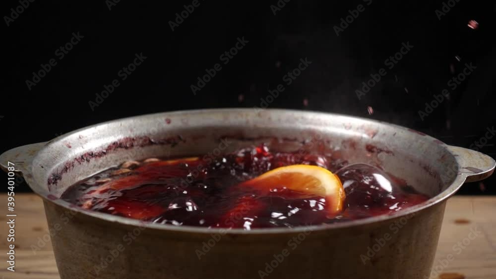 Slow motion of falling orange slice in mulled wine that preparing in big old metal kettle Slow motion of falling orange slice in mulled wine that preparing in big old metal kettle