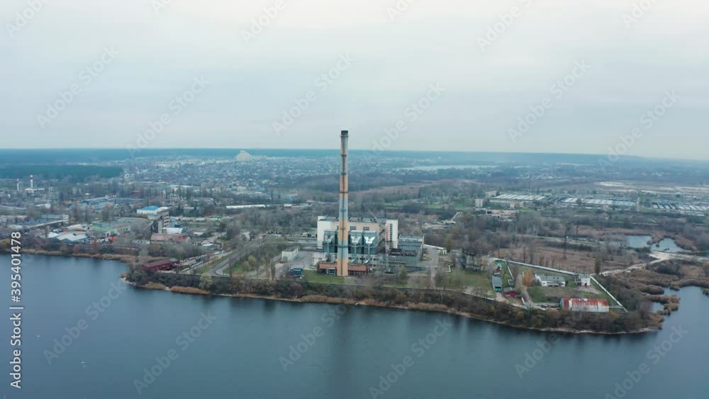 Aerial view of the Industrial Plant with Smoking Pipes near the City. Industrial zone. View from the drone to the Metallurgical factory near the river. Poor environmental conditions of the environment Aerial view of the Industrial Plant with Smoking Pipes near the City. Industrial zone. View from the drone to the Metallurgical factory near the river. Poor environmental conditions of the environment
