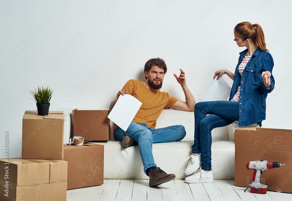 Cheerful man and woman on sofa at home interior moving boxes Cheerful man and woman on sofa at home interior moving boxes