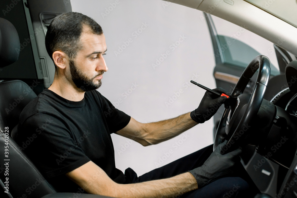 Car detailing and interior care concept. Young man, car wash worker, wearing protective rubber