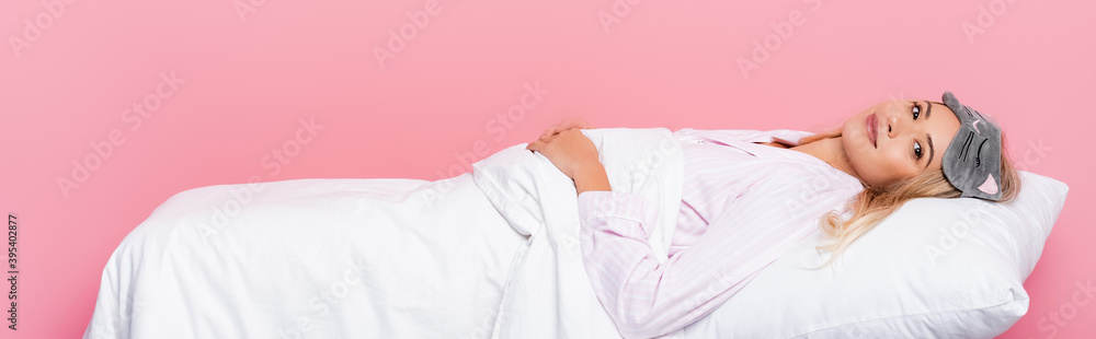 woman in pajamas lying on pillow with blanket on pink background, banner woman in pajamas lying on pillow with blanket on pink background, banner