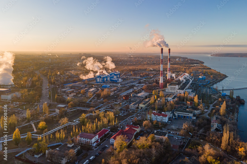 Factory chimneys producing smoke at sunrise, aerial view. Air pollution, environment and ecology crisis, climate change, global warming.