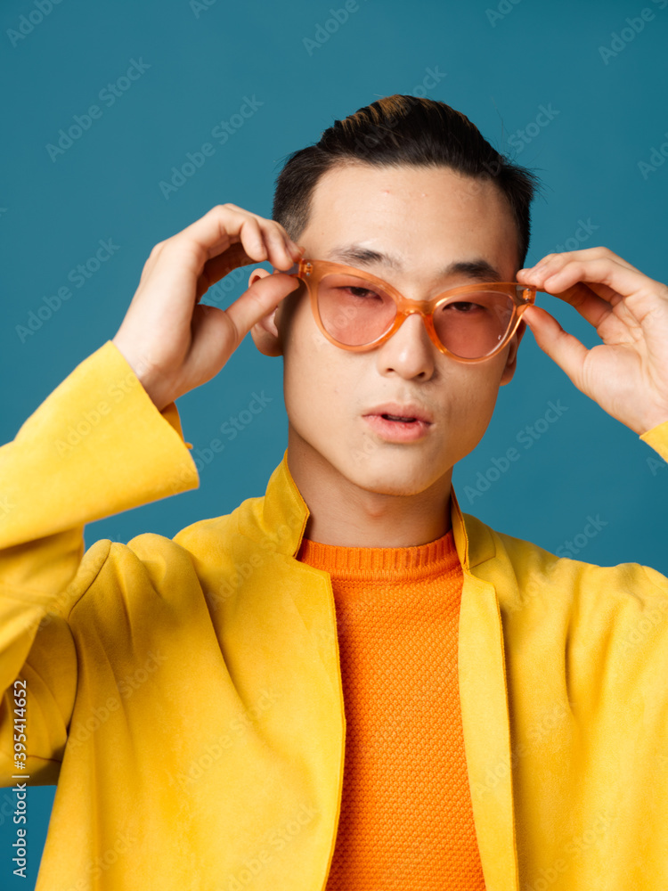 Man in sunglasses on a blue background and a yellow jacket model Man in sunglasses on a blue background and a yellow jacket model