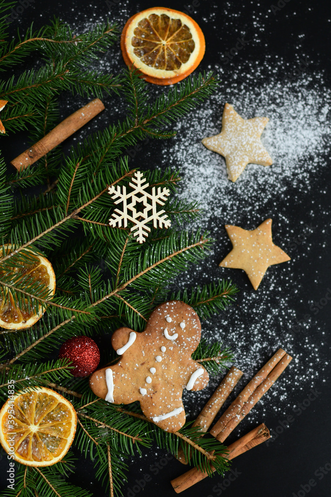 Naklejka premium Dark christmas background with snowflakes, spices, candy cane, fir tree and gingerbread cookies. Copy space for text.