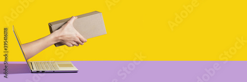 Giving a delivery package or a gift from the screen of the computer online yellow and purple background photo