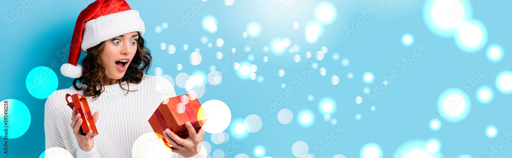 shocked woman looking at gift box near snow illustration on blue, banner shocked woman looking at gift box near snow illustration on blue, banner