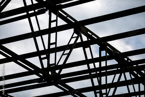Structure of steel roof frame for building construction on sky background.
