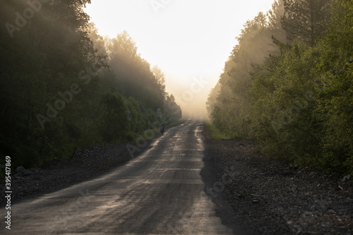 Picturesque landscape scene and sunrise above foggy road