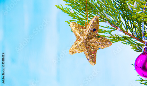 shiny golden star christmas ornament hanging on snowy pine tree branch
 (ID: 395418039)