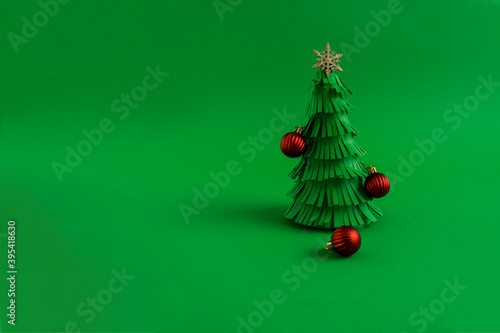 Green Christmas tree made of paper with red decorative balls. Minimal New Year concept