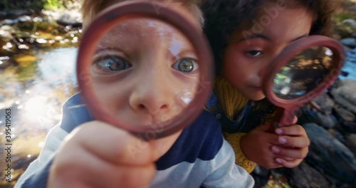 Small boy and girl looking at camera with magnifying glass