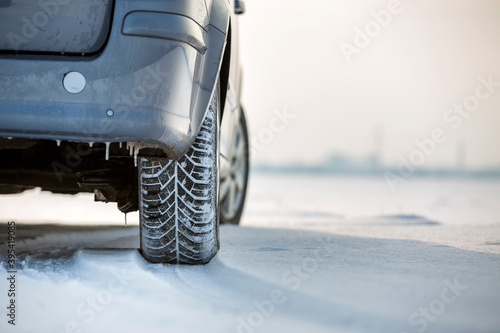 Close up of a car tire parked on snowy road on winter day. Transportation and safety concept. © bilanol