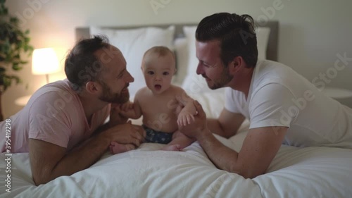 Male gay parents relaxing in bed with baby